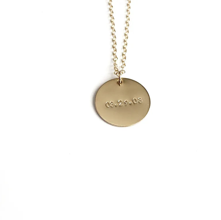 Gold necklace with a round pendant on a white background