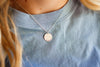 Necklace with a round pendant on a light blue shirt