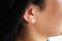 Adult wearing hammered square stud earrings