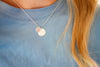 Necklace with two round pendants on a blue shirt background