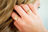 Close-up of a hand with gold rings near hair, on a blurred background