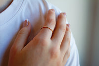 Hand wearing a gold ring on a white background