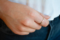 Close-up of a hand wearing a gold ring with a blurred background