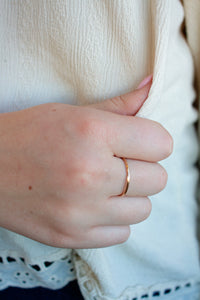 Close-up of a hand wearing a gold ring with a blurred background