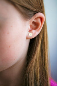 Child wearing a square stud gold earring