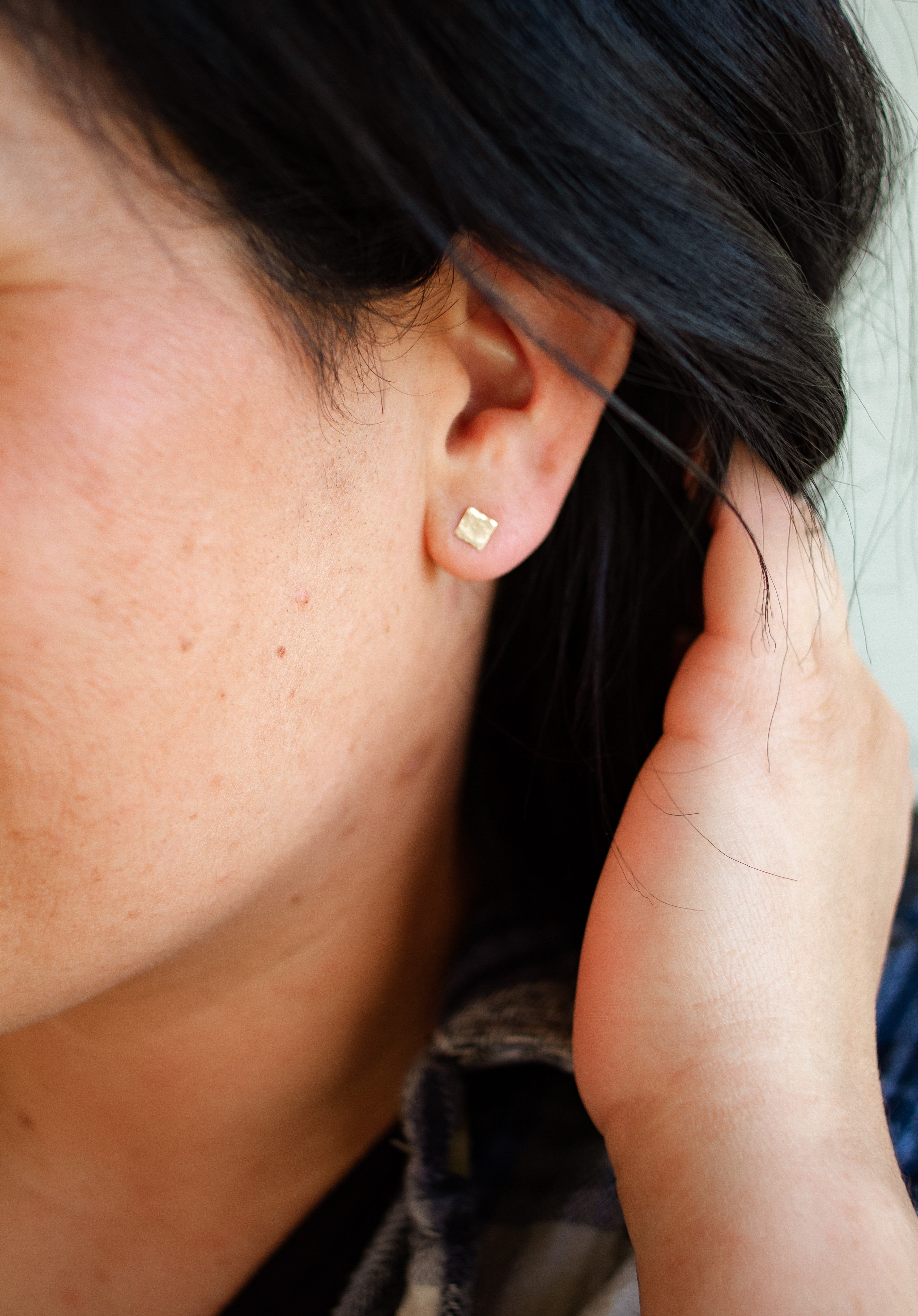Hammered square stud earrings in ear.