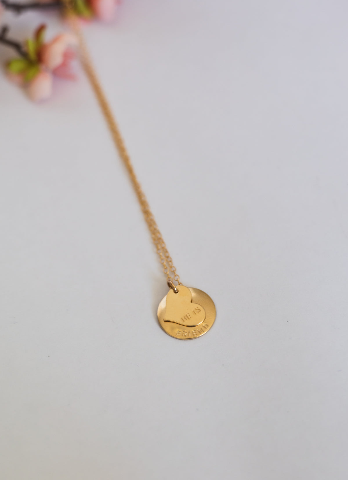 Gold necklace with a round pendant on a light gray background