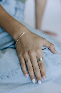 Hand with rings and a bracelet on a light blue denim background