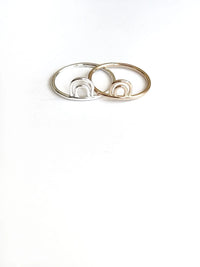 Two rings, one silver and one gold, on a white background