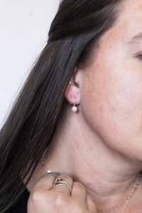 Close-up of a woman wearing a pearl earring with a neutral background