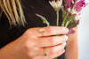 Hand holding a bouquet of flowers with gold rings on a blurred background