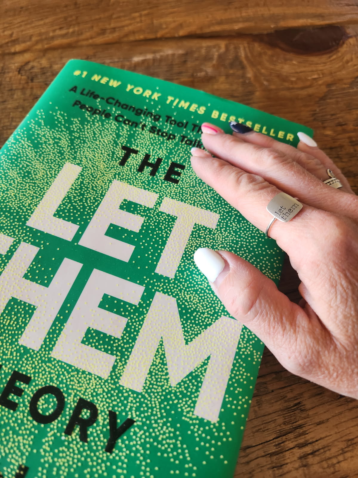 Hand with square personalized ring on green book.