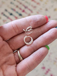 Two small gold rings held between fingers against a blurred background