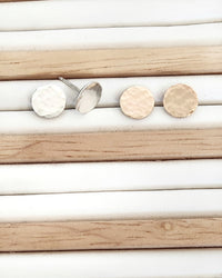 Pair of silver and gold round stud earrings on a striped background
