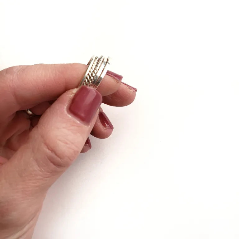 Hand holding a silver ring stack with a white background