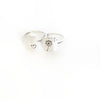 Two silver rings with heart and dandelion designs on a white background