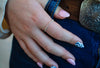 Close-up of a hand with rings on a blue denim background