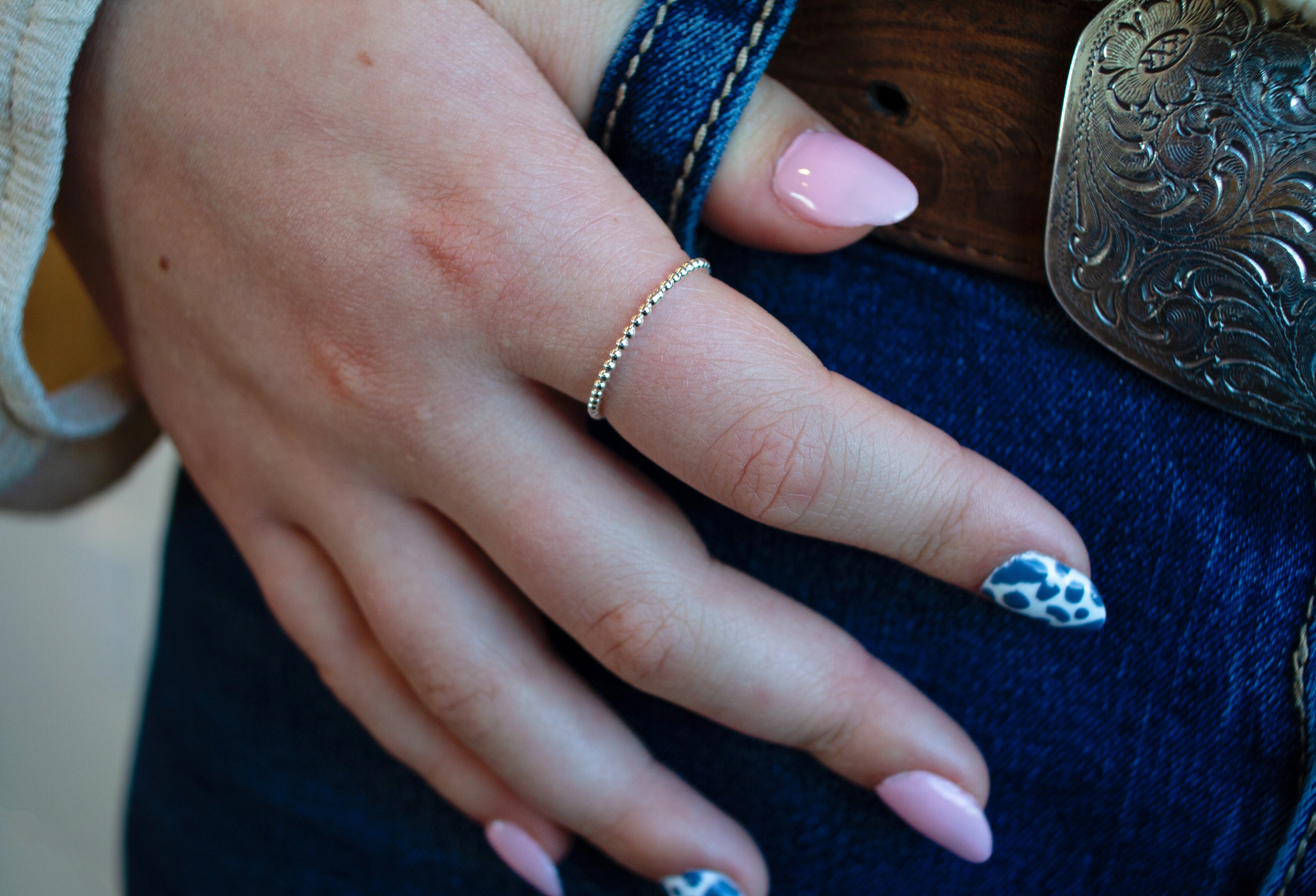 Close-up of a hand with rings on a blue denim background